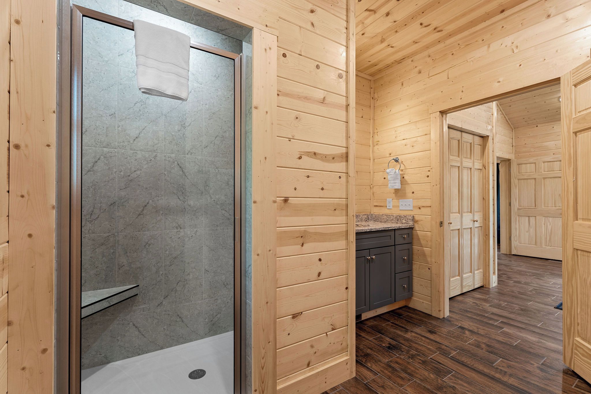 A wooden interior with a shower, a sink, and cabinets.