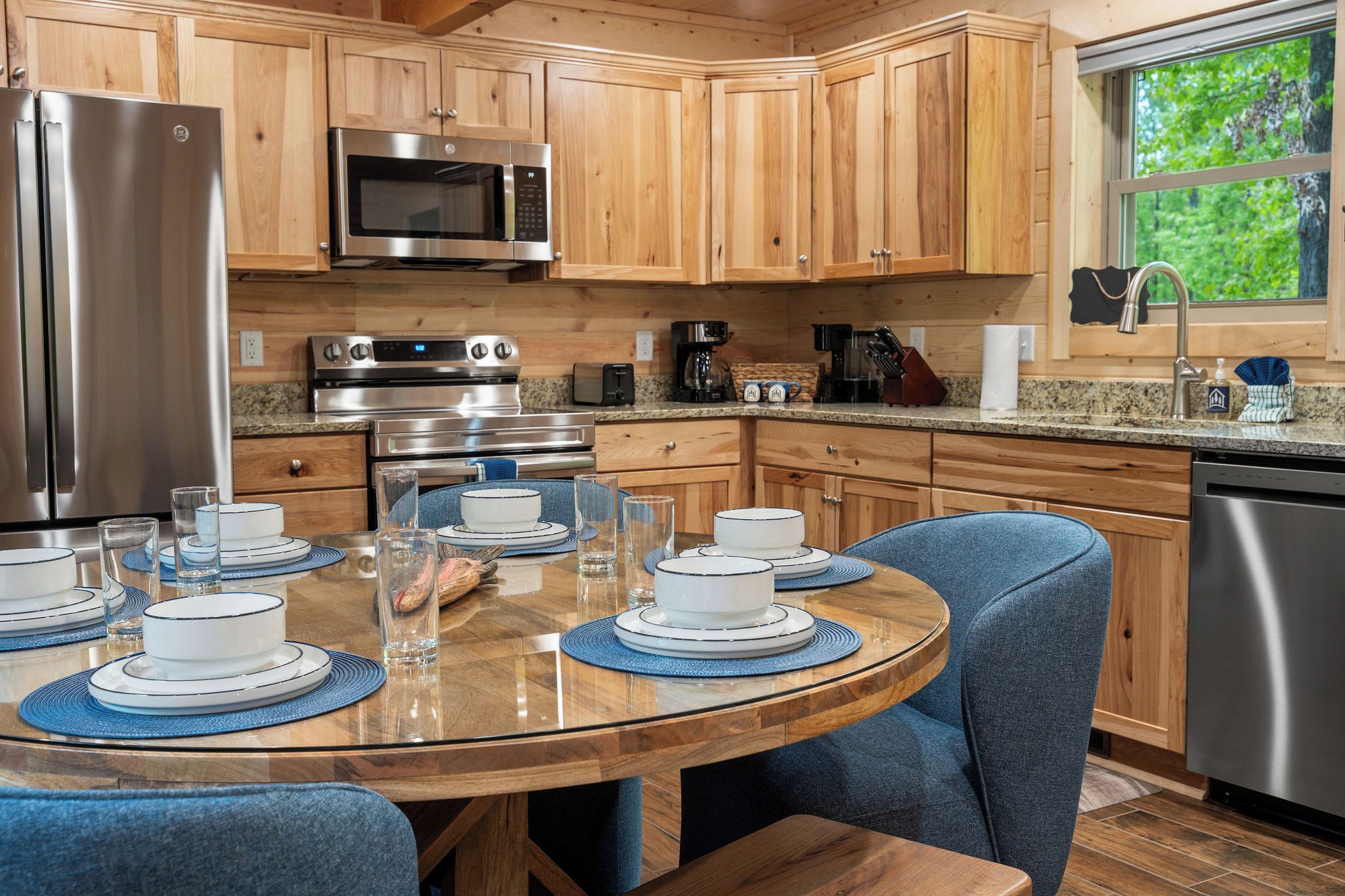 A modern kitchen with wooden cabinets, stainless steel appliances, and a dining table set for four.