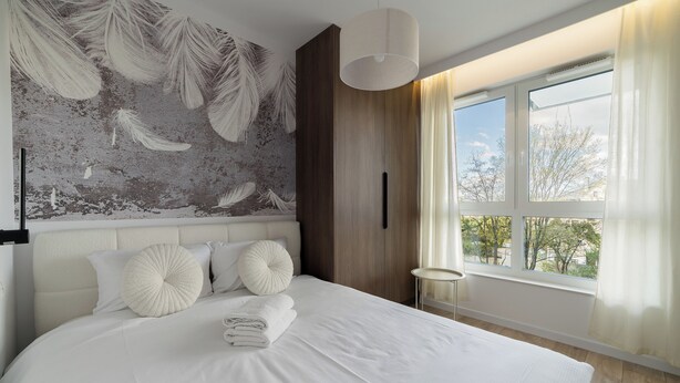 Ein modernes Schlafzimmer mit einem großen Bett, einer Wandmalerei, einem Fenster mit Vorhängen und einem Nachttisch.