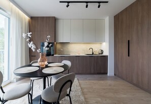 Une cuisine moderne avec des meubles en bois, un coin repas avec une table ronde et des chaises, et un vase rempli de fleurs.