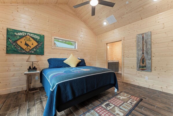 Ein Schlafzimmer mit Holzwänden, einem Bett, einem Nachttisch, einer Lampe und einem Wandschild.