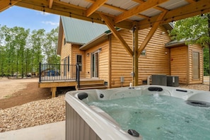 Eine Blockhütte mit Whirlpool, Holzterrasse und überdachtem Außenbereich.