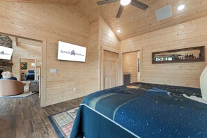 A wooden interior with a bed, a ceiling fan, and a sign for RENTBRINSON.com. - True Log Cabin Near Thunder Ridge & Big Cedar_Pvt Hot Tub_Free Attraction Tickets_Bonus Loft (Ridgedale)