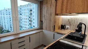 A modern kitchen with wooden cabinets, a built-in stove, and a window overlooking a residential area.
