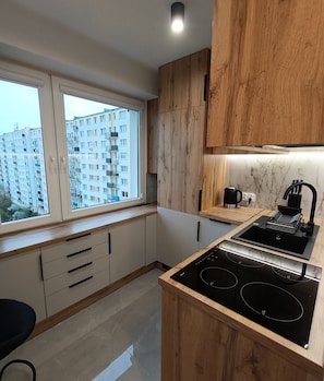 Una cocina moderna con armarios de madera, estufa integrada y ventana con vistas a una zona residencial.