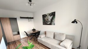 A modern living room with a sofa, dining table, chairs, and a painting on the wall.