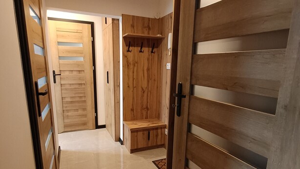 A hallway with wooden doors and a bench.
