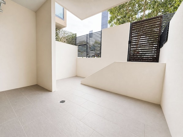 A modern, minimalist balcony with a clean floor, a metal railing, and a view of greenery and buildings. - Rosehill 1BR | Bunk Bed | Max 3 | near Parramatta (Rosehill)