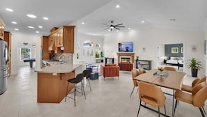 A spacious kitchen with a central island, dining area with chairs, and a fireplace.