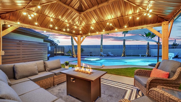 An outdoor patio with a pool, lounge seating, and a fire feature.