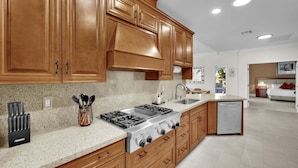 A modern kitchen with wooden cabinets, a gas stove, a dishwasher, and a granite countertop.