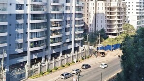 Un edificio residenziale a più piani con balconi, una strada con auto e un cielo sereno.