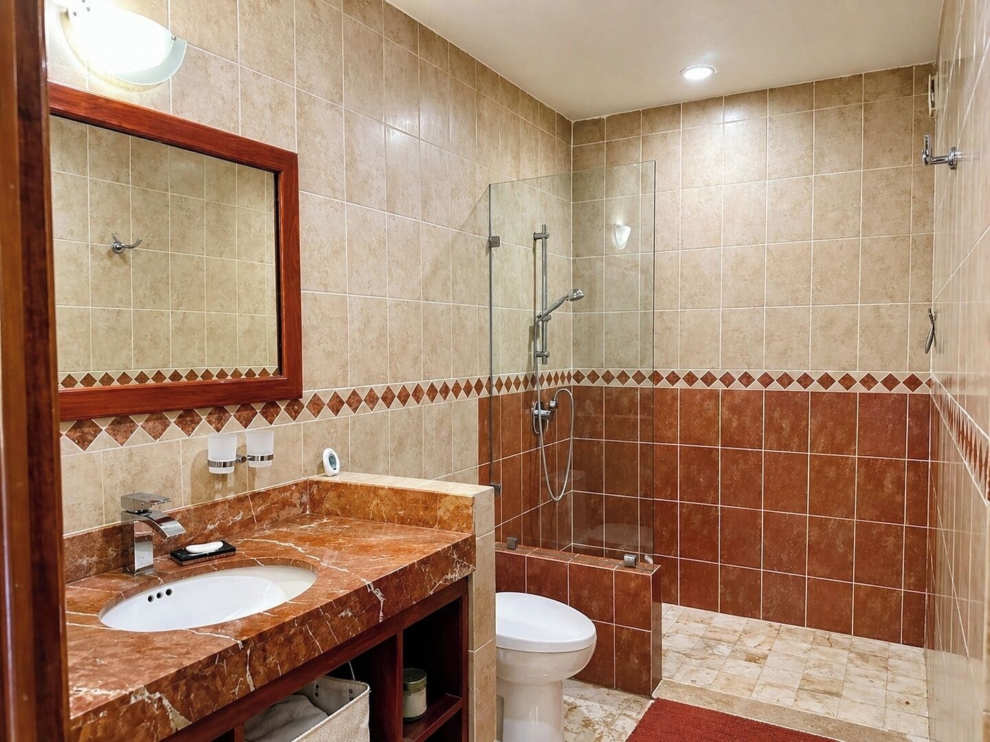 A bathroom with a marble sink, a toilet, a shower, and a mirror.