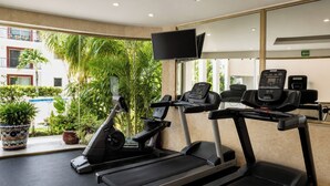 Ett gym med löpband, motionscyklar och en tv-skärm.