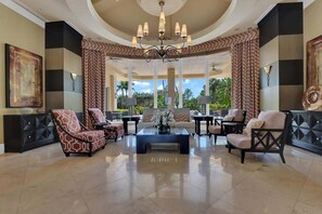 Eine geräumige Lobby mit einem zentralen Couchtisch, verschiedenen Sitzgelegenheiten, großen Fenstern und einem Kronleuchter.