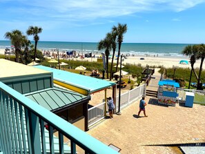 A beachside view with a building, palm trees, and a sandy beach. - Seaside Escape 2 Queen Efficiency in Sand Dunes Resort (Myrtle Beach)