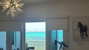 Et værelse med et teleskop, en stol og udsigt over havet.