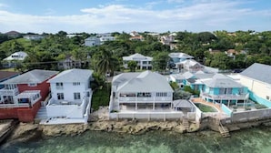 Et kystnære boligområde med huse, en swimmingpool og fri udsigt over havet.