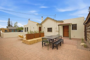 A patio with a table and chairs, a wooden bench, and a small garden area. - Stay at Hey House! - King suite #1 (Buena Vista)