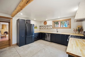 A modern kitchen with dark cabinets, a built-in stove, and a window with a view. - Stay at Hey House! - King suite #1 (Buena Vista)