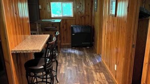 A wooden interior with a kitchen area, a dining table with chairs, and a built-in stove.