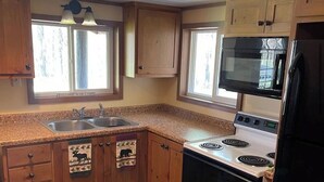 A kitchen with wooden cabinets, a stove, a microwave, and a sink.