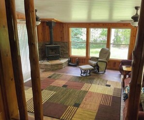 Une pièce chaleureuse avec une cheminée en pierre, une grande fenêtre et un tapis à motifs.