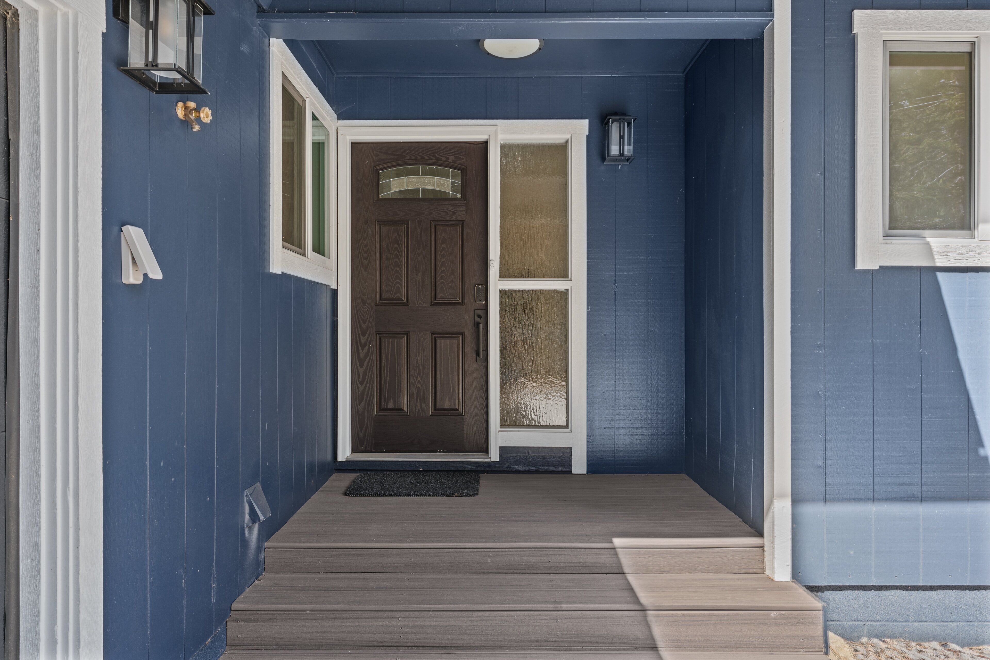A blue exterior with a brown door, a small porch, and a white mailbox.