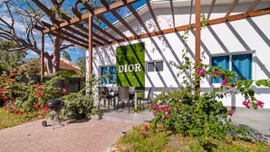 A patio area with a pergola, outdoor seating, and a garden with flowers.