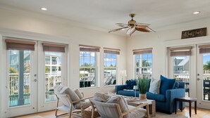 A spacious living room with a view of a pool, a ceiling fan, and a sign that reads 'The Seagrove Family.' - Dolphin Paradise: Pool, Elevator, Waterfront with Dock (Key Largo)