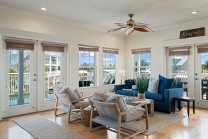 A spacious living room with a view of a pool, a ceiling fan, and a sign that reads 'The Seagrove Family.' - Dolphin Paradise: Pool, Elevator, Waterfront with Dock (Key Largo)