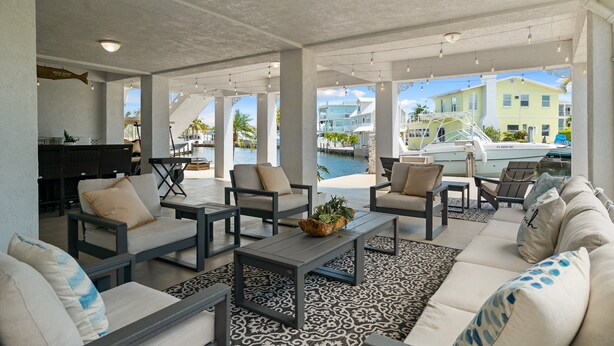 An open-plan living area with a pool view, outdoor seating, and a boat dock. - Dolphin Paradise: Pool, Elevator, Waterfront with Dock (Key Largo)