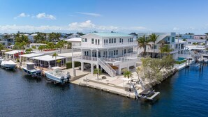 A waterfront property with a multi-level house, docked boats, and a marina. - Dolphin Paradise: Pool, Elevator, Waterfront with Dock (Key Largo)