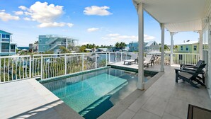 A rooftop pool with a view of surrounding buildings, a covered patio area with lounge chairs, and a clear blue sky. - Dolphin Paradise: Pool, Elevator, Waterfront with Dock (Key Largo)