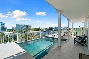 A rooftop pool with a view of surrounding buildings, a covered patio area with lounge chairs, and a clear blue sky. - Dolphin Paradise: Pool, Elevator, Waterfront with Dock (Key Largo)