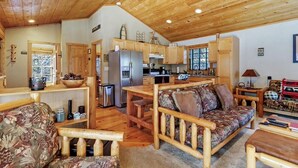 Interior acogedor de una cabaña con una mesa de comedor de madera, un sofá, una cocina y una sala de estar.