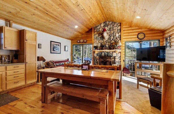 A wooden interior with a stone fireplace, wooden furniture, and a television.