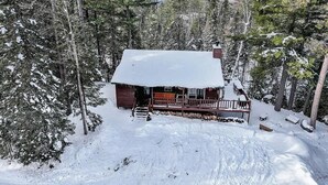 Una cabaña rodeada de árboles cubiertos de nieve.