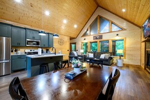 Eine geräumige Küche mit modernen Geräten, ein Essbereich mit Holztisch und ein gemütliches Wohnzimmer mit Kamin.