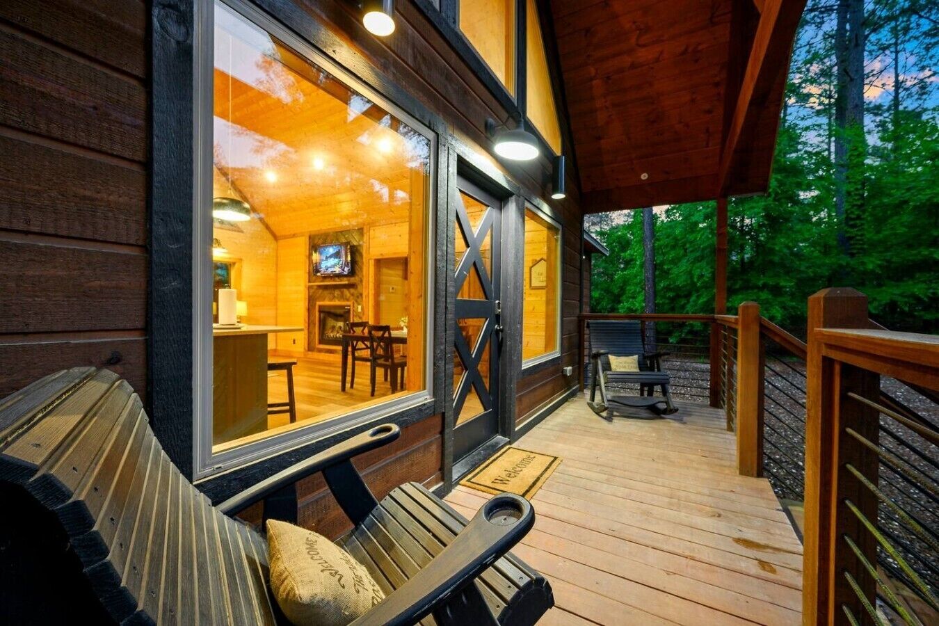 A wooden cabin with a deck, a fireplace, and a television in the living area.