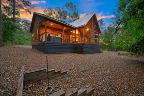 Eine Hütte mit Veranda, großen Fenstern und einer Schotterzufahrt.