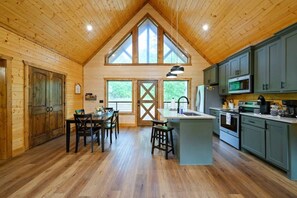 Ein Blockhaus-Interieur mit Essbereich, Küche und großen Fenstern.