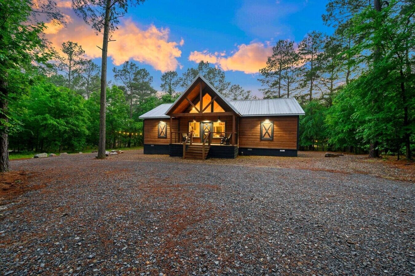 Une cabane avec une allée en gravier, un revêtement extérieur en bois et un toit en métal.