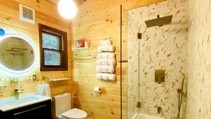 Puisesta mökistä löytyvä kylpyhuone, jossa on kylpyamme, pesuallas, wc ja peili.