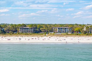 A beach with buildings in the background, a sandy shore, and clear skies. - Beach Resort Stay | Ocean Views, Pool, Bunk Beds, Sleeps 7, Walkable to Coligny Plaza! (Hilton Head Island)