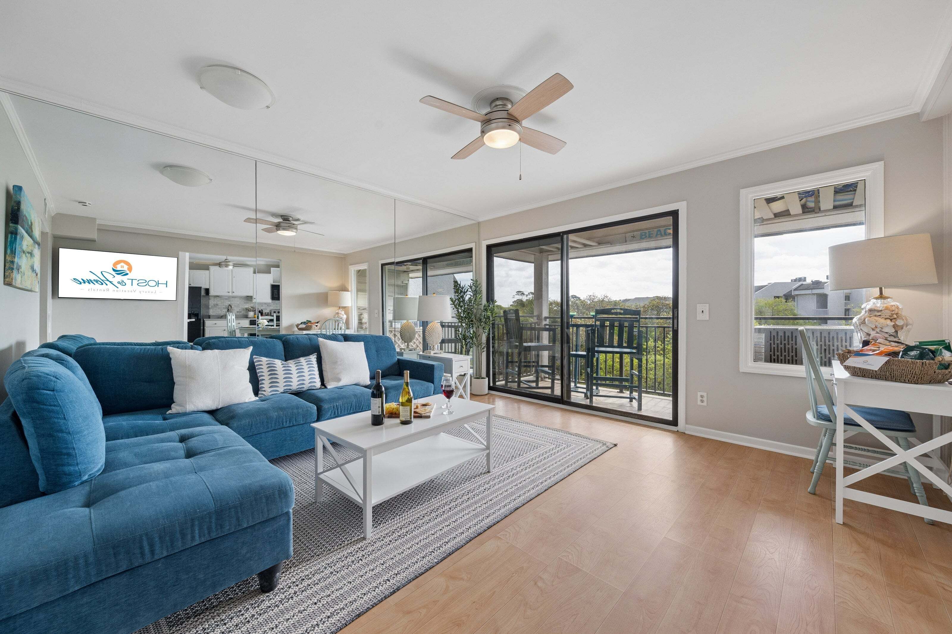 A modern living room with a blue sofa, a white coffee table, and a ceiling fan.