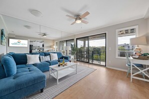 A modern living room with a blue sofa, a white coffee table, and a ceiling fan. - Beach Resort Stay | Ocean Views, Pool, Bunk Beds, Sleeps 7, Walkable to Coligny Plaza! (Hilton Head Island)
