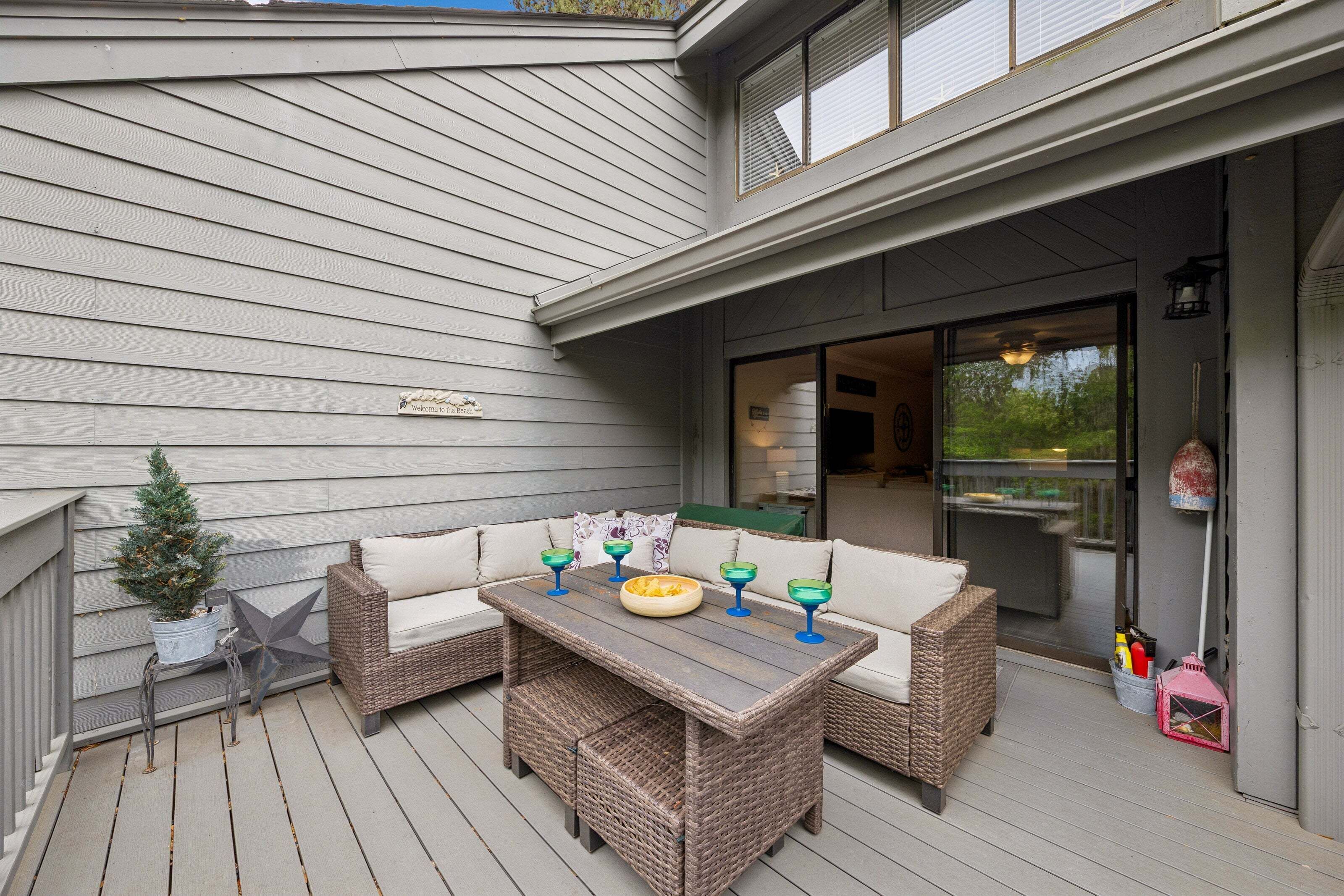 A covered patio with wicker furniture, a small Christmas tree, and outdoor lighting.