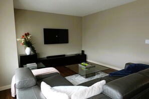 Una sala de estar moderna con un sofá, una mesa de centro y un televisor de pantalla plana montado en la pared.