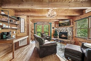Ein gemütliches Blockhaus-Interieur mit Kamin, Holzwänden, einer Couch und einer Kaffeestation.